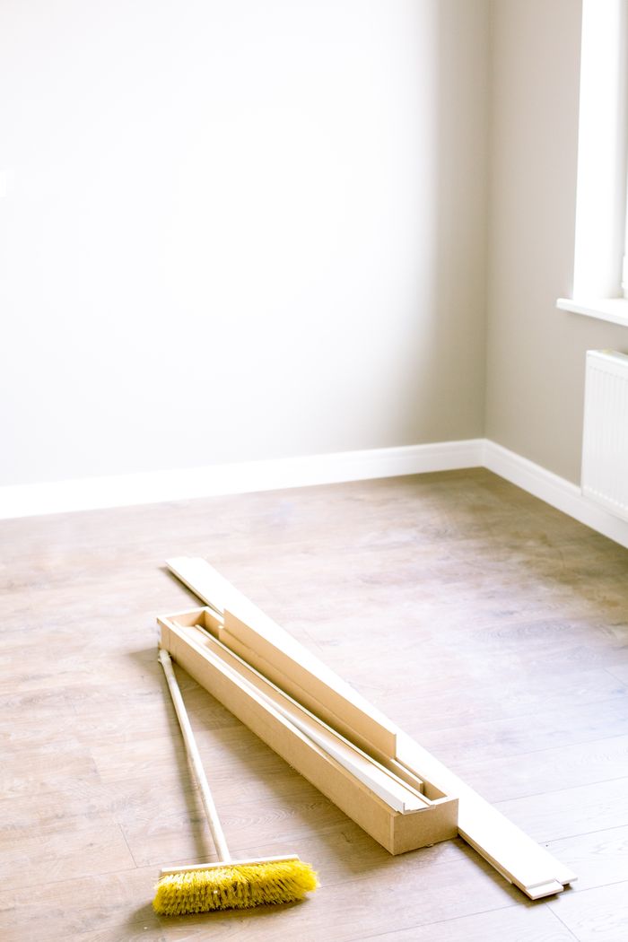 Une pièce vide avec des planches en bois et un balai, prête à être rénovée.
